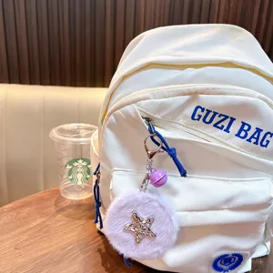Plüsch-Schlüsselanhänger mit sternförmigem Klappspiegel an weißem Rucksack im Café.