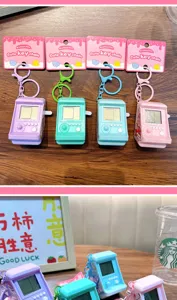 Close-up of colorful retro mini arcade machine keychains in a cafe lifestyle setting.