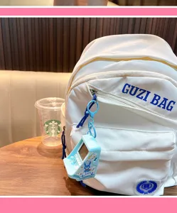 Detailed view of a blue mini arcade game keychain hanging on a white fabric backpack
