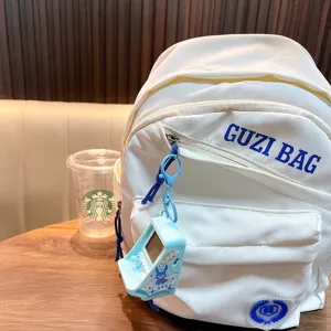 Portable Tetris game console keychain on white backpack in cafe setting