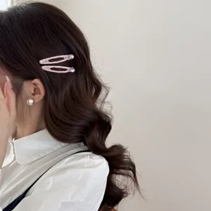 Dettaglio ravvicinato di fermagli per capelli a scacchi rosa con strass su capelli ondulati