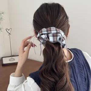 Vintage style plaid fabric scrunchie with delicate ribbon ties shown on a model's hair