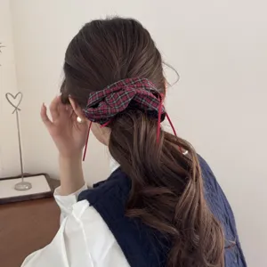 Detailed view of vintage plaid scrunchie with red ribbons on a dark ponytail
