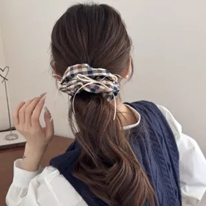 Detailed view of a vintage dark plaid scrunchie with white ribbon accents on a ponytail