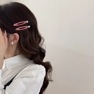Dettaglio di fermagli per capelli a scacchi rossi con strass blu su capelli mossi.
