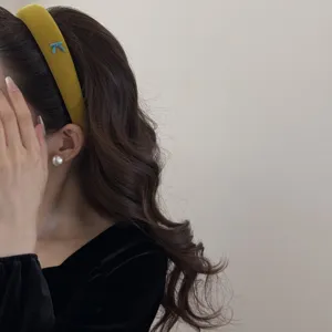 Detail view of mustard yellow velvet sponge headband with blue bow on model