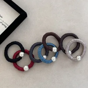 Macro view of multi-colored silk hair ties with metallic pearl beads decorative details.