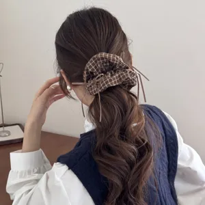Macro view of vintage dark plaid hair scrunchie with ribbon accents on a brown wavy ponytail