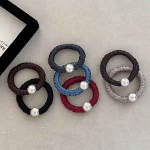 Macro detail of seven colorful silk scrunchies with elegant silver beads on grey background.