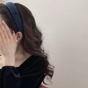 Detailed side view of an elegant blue velvet sponge headband with a small red bow detail