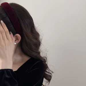Detailed view of elegant burgundy velvet sponge headband with bow on brown wavy hair