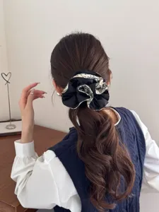 Detail view of a French vintage black and white printed scrunchie used on long wavy hair