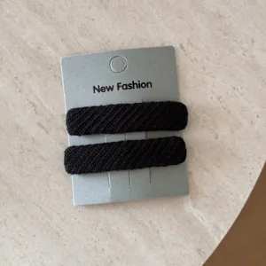 Dettaglio di fermagli per capelli rettangolari in tessuto twill nero su carta
