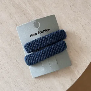 Dettaglio di fermagli per capelli rettangolari in saia blu scuro su cartoncino grigio