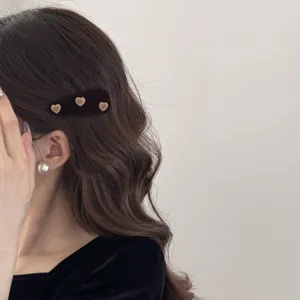 Gros plan d'une barrette à cheveux triangulaire en velours marron avec de jolis petits cœurs