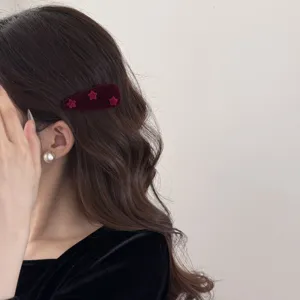Détail d'une pince à cheveux vintage en velours bordeaux avec étoiles sur cheveux bouclés