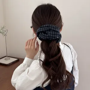 Primer plano de un coletero de cuadros grises sobre un peinado de trenza muy elegante