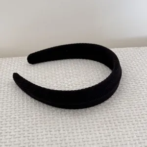 Close-up of black corduroy padded headband showing ribbed texture and high-top design