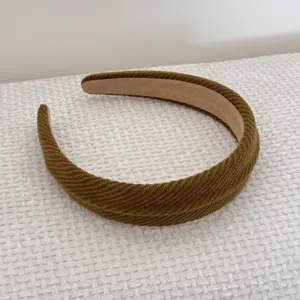 Detail view of an olive brown sponge headband with ribbed texture on white fabric.