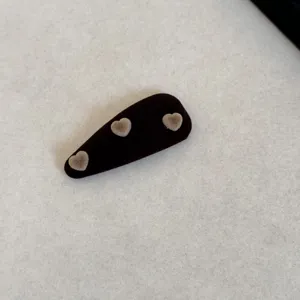 Gros plan détaillé de la pince à cheveux en velours noir ornée de trois petits cœurs floqués.