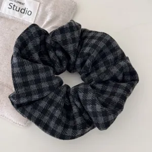 Vista detallada de coletero grande a cuadros grises tipo houndstooth con textura de tela suave