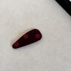 Zoom sur une barrette à cheveux en velours bordeaux ornée de trois étoiles en relief 3D.