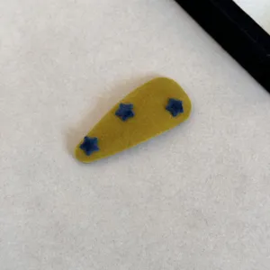 Détail d'une pince à cheveux BB vintage en velours jaune moutarde avec étoiles bleues