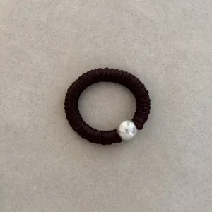 Close-up detail of a dark brown silk hair scrunchie with a large silver metallic bead.