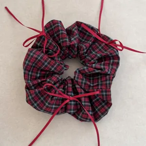 Detailed view of a vintage red plaid scrunchie featuring elegant red ribbon bows.
