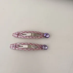 Primo piano di due fermagli per capelli BB a scacchi rosa con strass viola decorativi