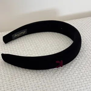 Detailed macro view of black velvet padded headband with a dainty burgundy bow detail.