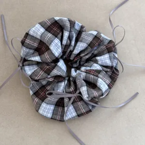 Detail of vintage preppy plaid scrunchie featuring multiple delicate grey ribbon bow accents