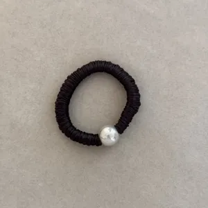 Close-up of black silk-like scrunchie with single white pearl bead detail
