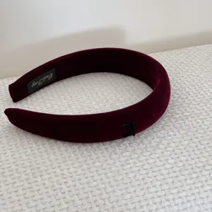 Close-up view of elegant burgundy velvet sponge headband with black bow and internal label