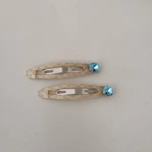Vista dettagliata di due eleganti fermagli per capelli a quadretti con strass blu