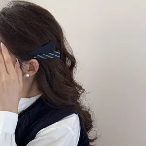 Dettaglio di eleganti fermagli per capelli in tessuto blu scuro su capelli castani mossi