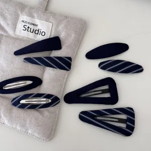 Vista dettagliata di fermagli per capelli in tessuto blu navy e a righe su sacchetto di lino