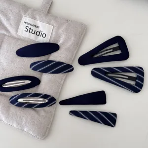 Dettaglio di fermagli per capelli in tessuto blu scuro con motivi a righe e tinta unita
