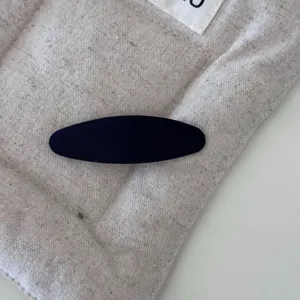 Primo piano di una clip per capelli ovale in tessuto blu navy su un astuccio di lino