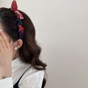 Close-up of a sweet red polka-dot bow headband worn by a woman with wavy brown hair.