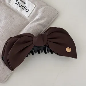 Close-up of a luxury brown satin bow banana hair clip with a golden 'HANDMADE' charm.