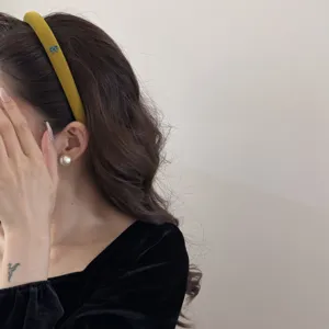 Detail of vintage mustard yellow velvet headband with small bow detail on Asian model.
