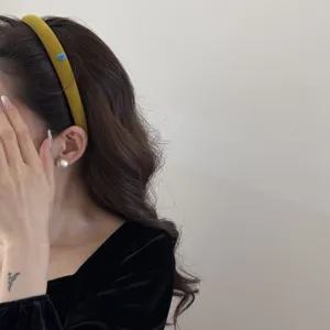 Vue détaillée d'un serre-tête floqué jaune moutarde avec un cœur bleu sur modèle.