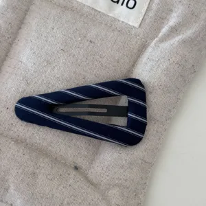 Dettaglio ravvicinato della clip per capelli triangolare rivestita in tessuto gessato blu