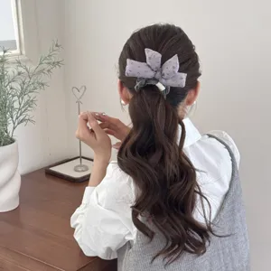 Close-up detail of a vintage purple floral padded bow scrunchie worn in a ponytail hairstyle