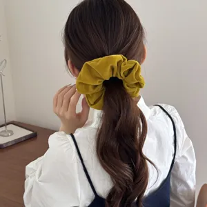 Detailed macro view of a vintage mustard yellow velvet hair scrunchie on a low ponytail