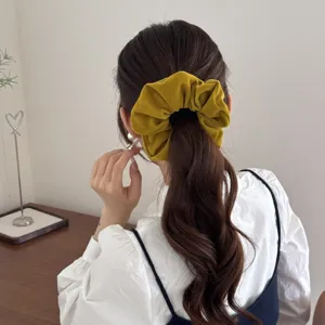 High-quality detailed view of a mustard yellow velvet scrunchie worn in a low ponytail style
