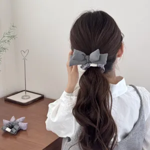 Detail shot of a padded bow hair scrunchie worn on a brown ponytail.
