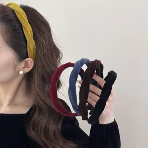 Model wearing a mustard yellow velvet twisted headband while holding other color options