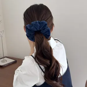 Close-up of a premium dark blue velvet scrunchie styled on a low ponytail hairstyle.